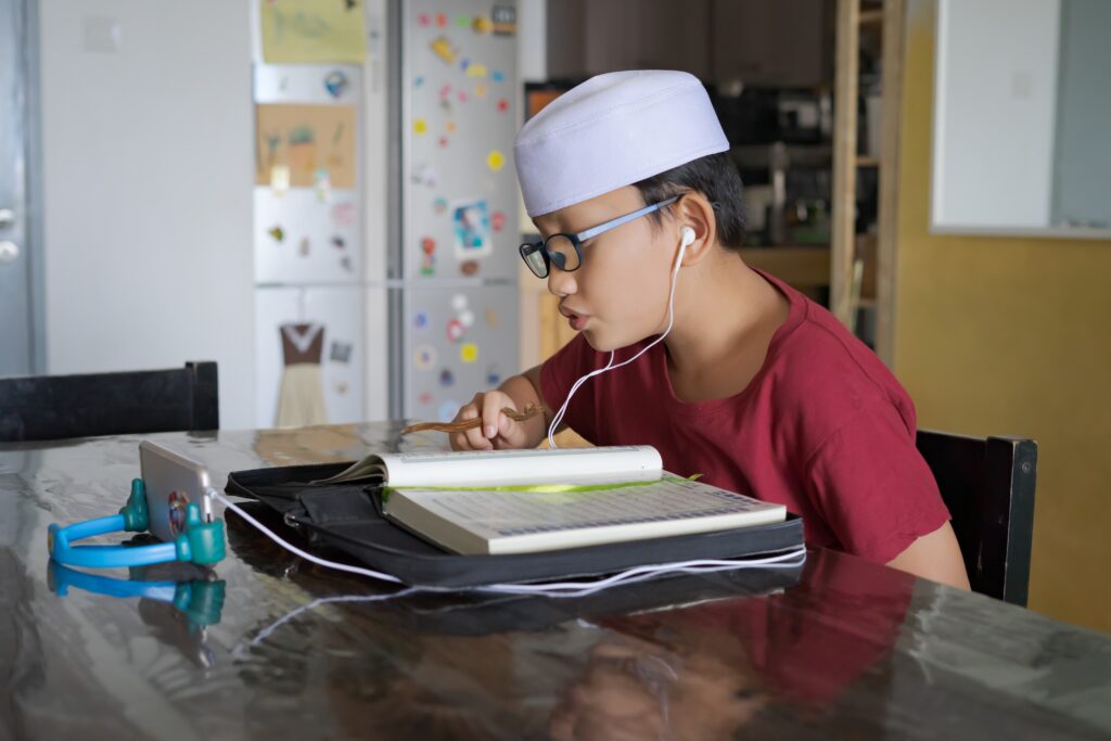 asian kid reading al quran through video call using smartphone d asian kid reading al quran through video call using smartphone d